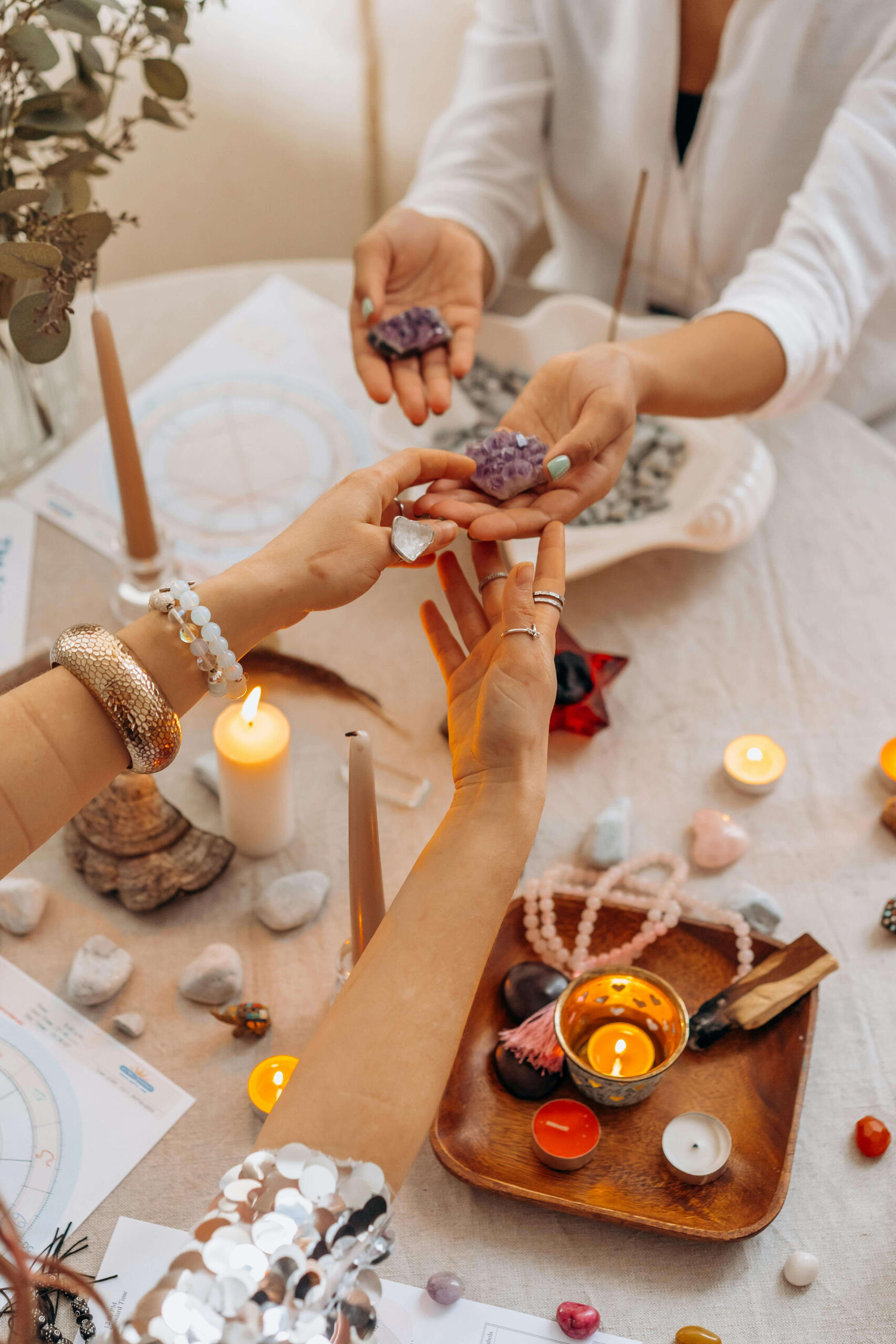 Crystal healing training Photo of two women holding crystals at a table with healing crystals, cancles and manifestation crystals.