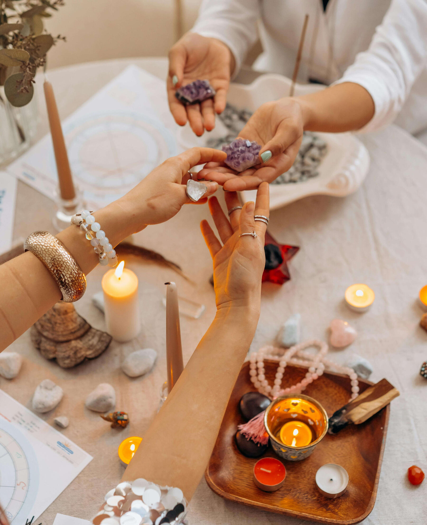 Crystal healing courses Photo of two women holding crystals at a table with many crystals, cancles and mala beads.