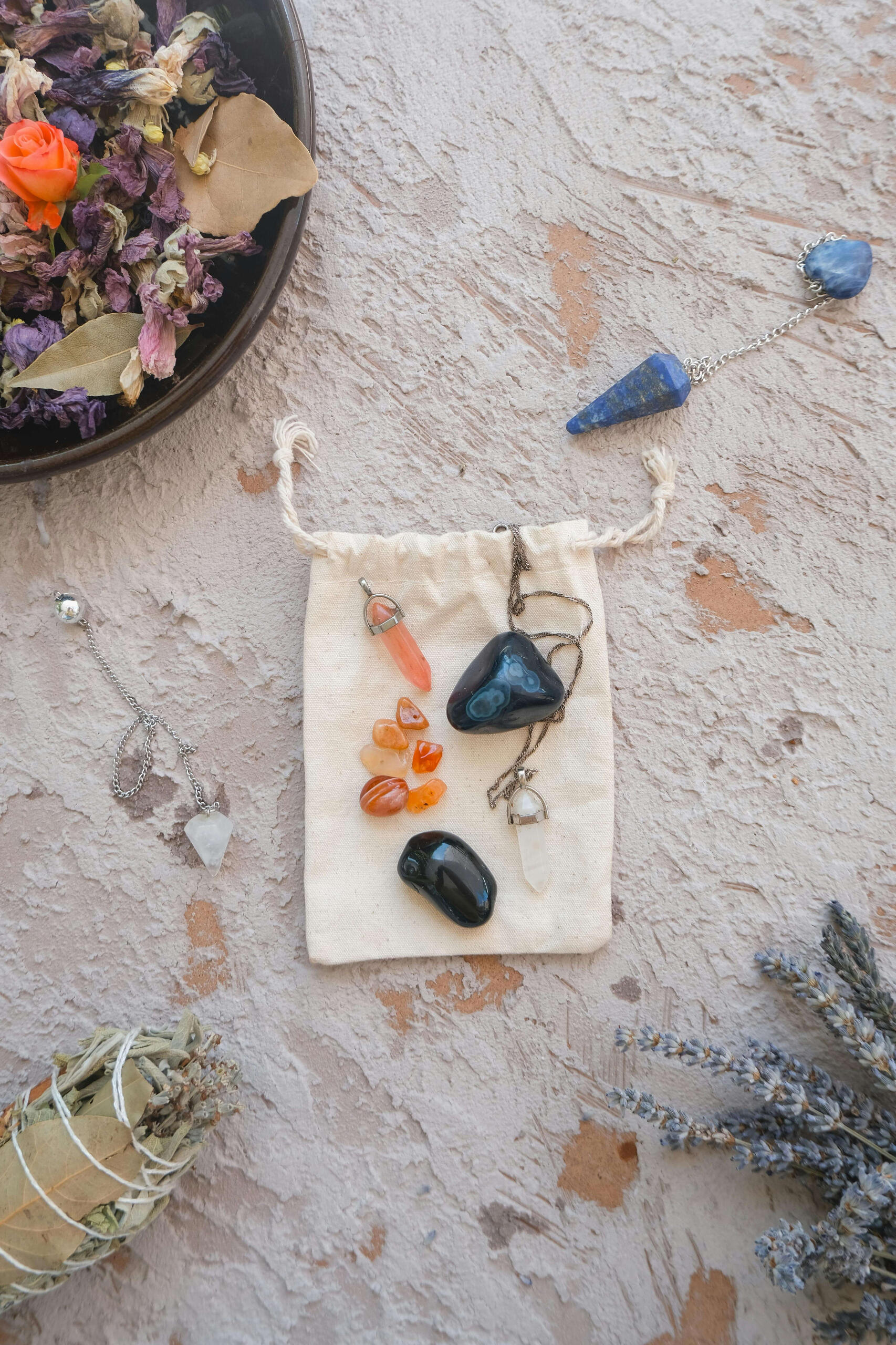 Crystal healing sessions This is a photo of some crystals and two crystal pendulums on top of a jute bag